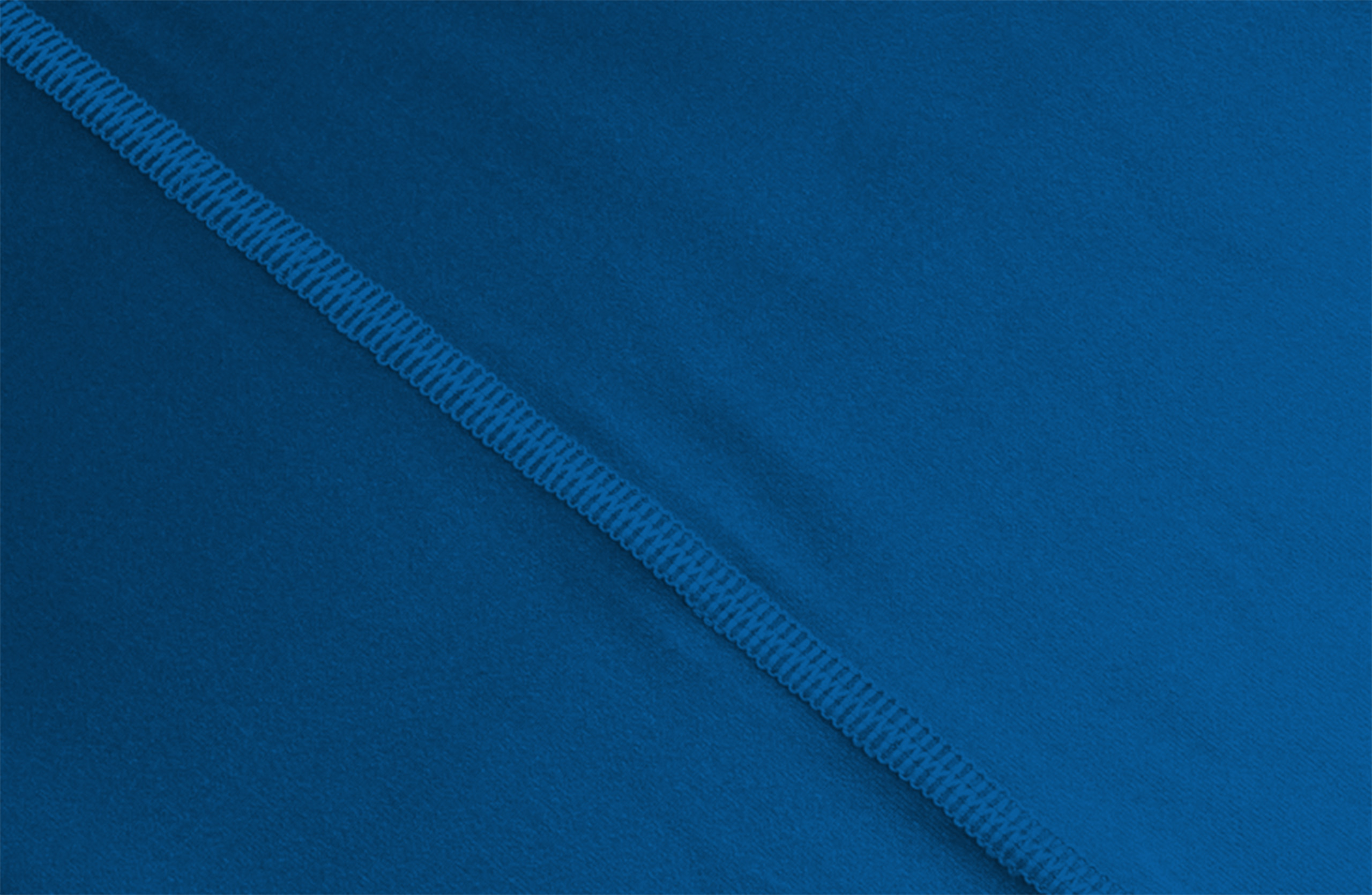 Detailaufnahme eines blau bedruckten Multifunktionstuchs mit feiner Mikrofaserstruktur und sichtbarer Naht entlang der Kante.
