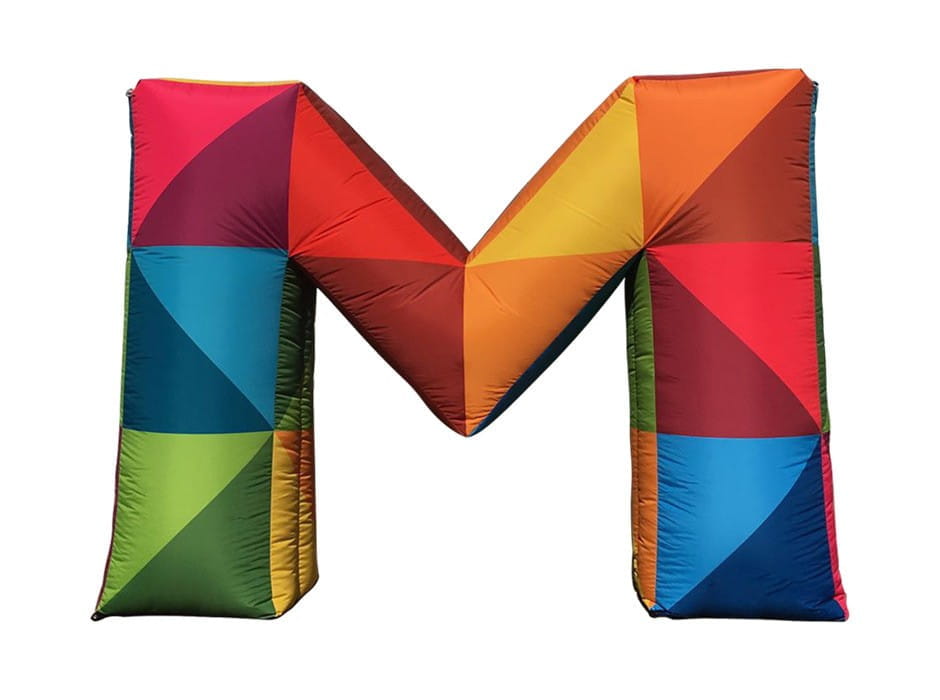 Aufblasbares 'M' in bunten Farben Bunte, aufblasbare Buchstaben 'M' in verschiedenen Farben und geometrischen Mustern.