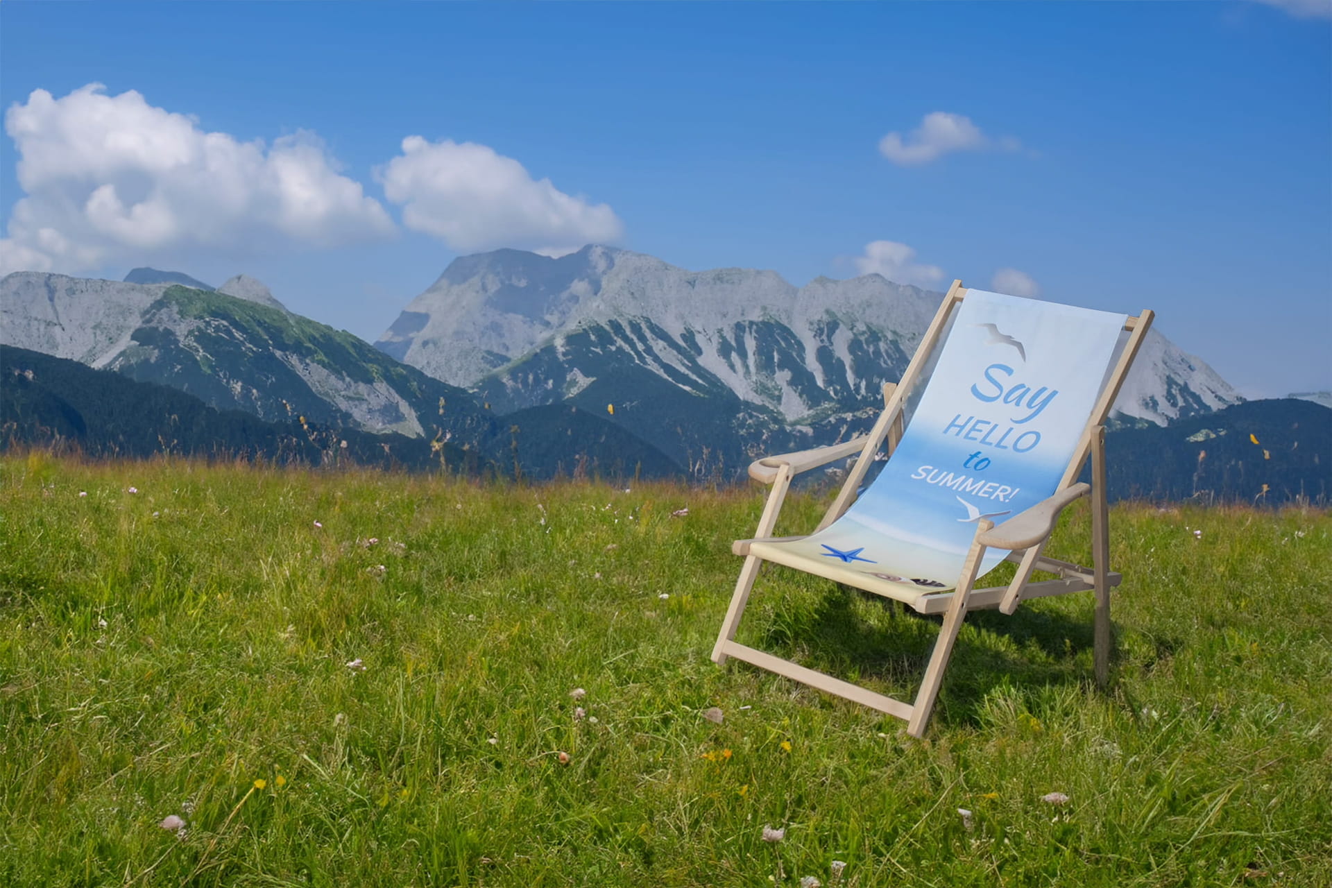 Liegestuhl mit bedrucktem Stoff auf einer Wiese vor Bergen