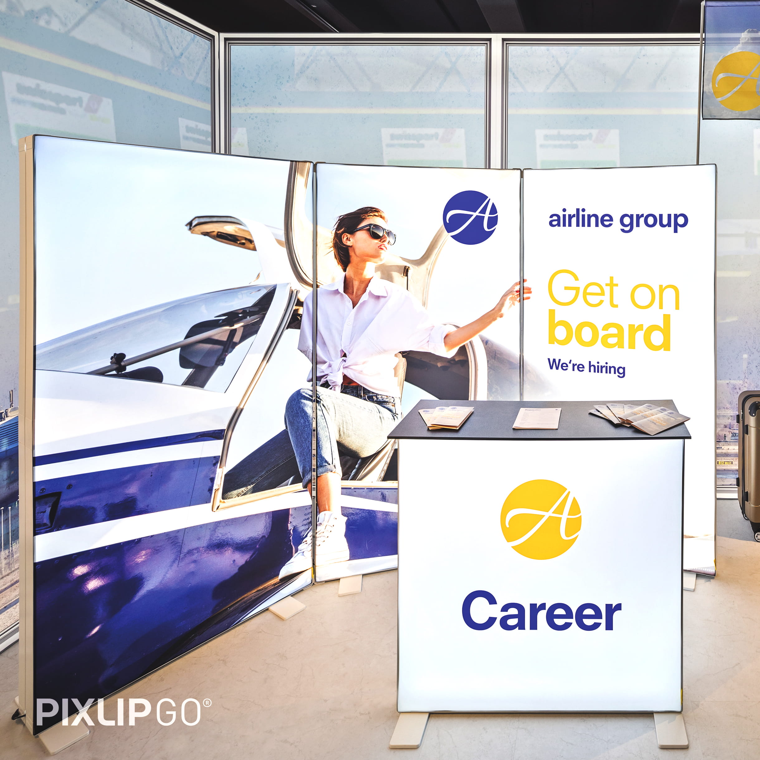 Ein Messestand am Flughafen mit einer beleuchteten Theke und drei Rückwänden.