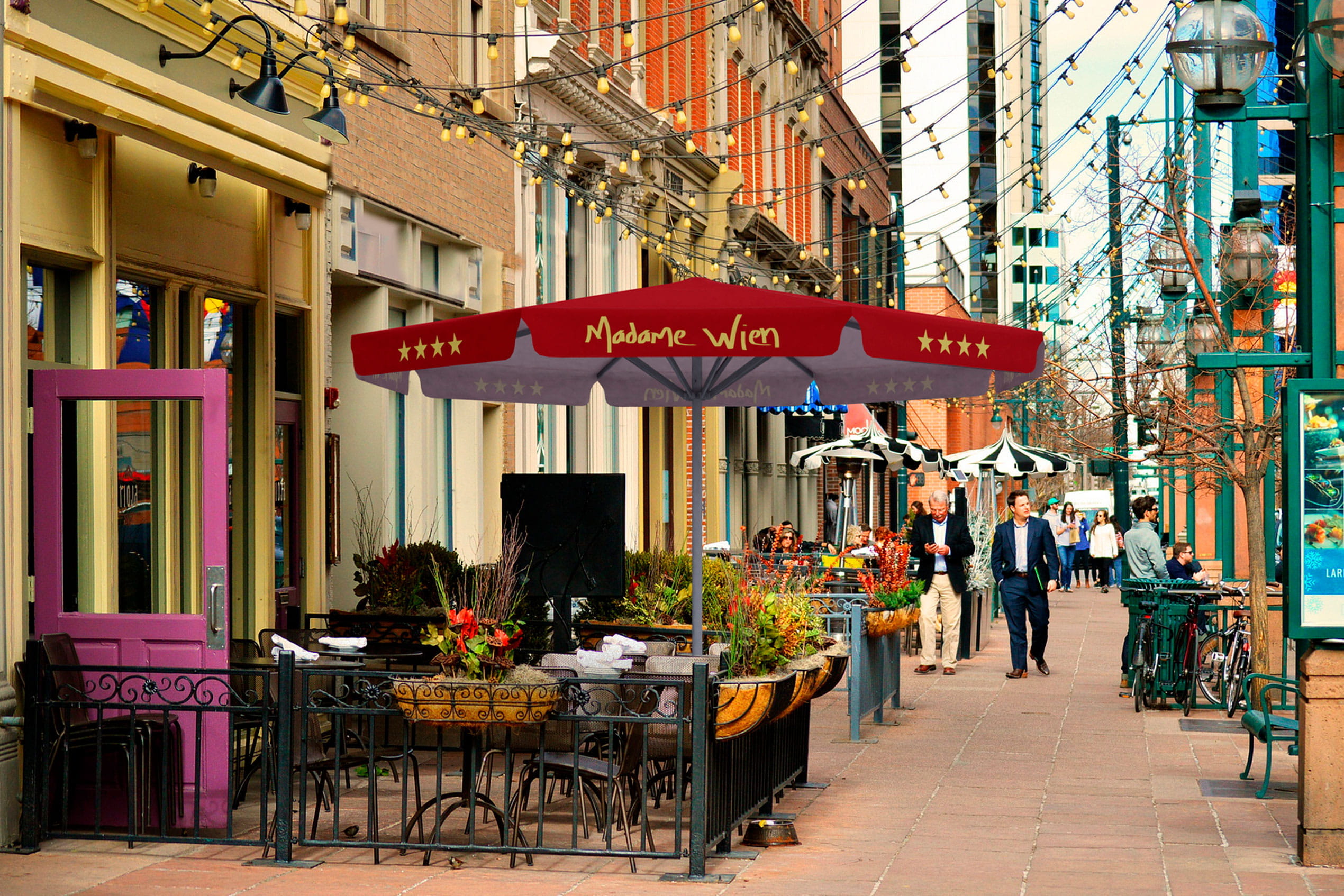 Sonnenschirm Expert Madame Wien Sonnenschirm 'Expert Madame Wien' über einem Restaurant im Freien, umgeben von Pflanzen und beleuchteten Straßen.