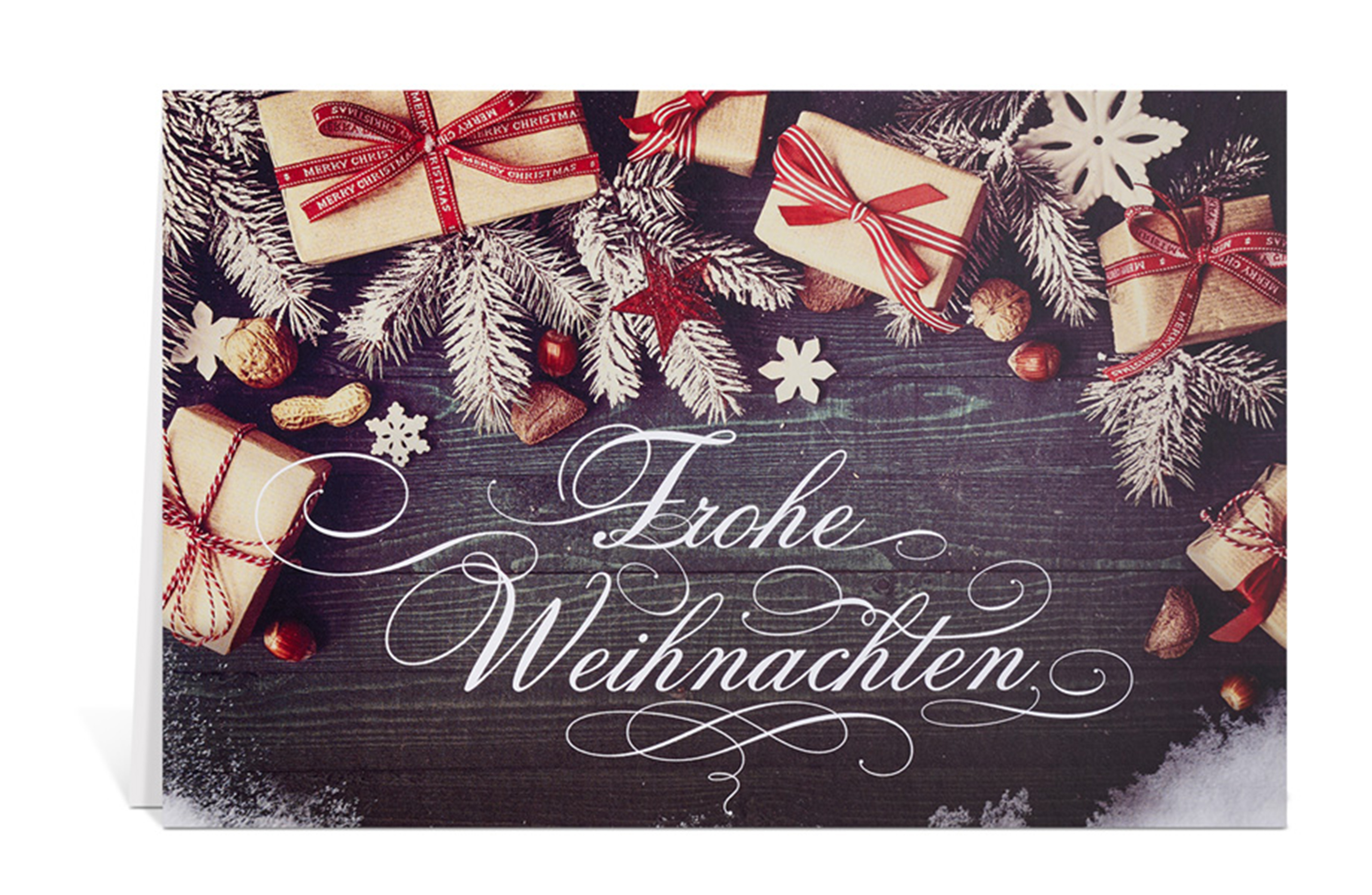Weihnachtskarte mit einem Tisch voller Geschenke, Nüsse und Tannenzweige und dem Text: Frohe Weihnachten
