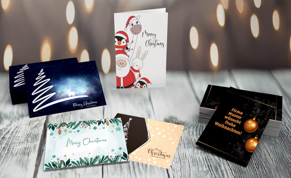 Gruss- und Postkarten Verschiedene Grußkarten mit Weihnachtsmotiven auf einem Holztisch mit Lichterketten im Hintergrund