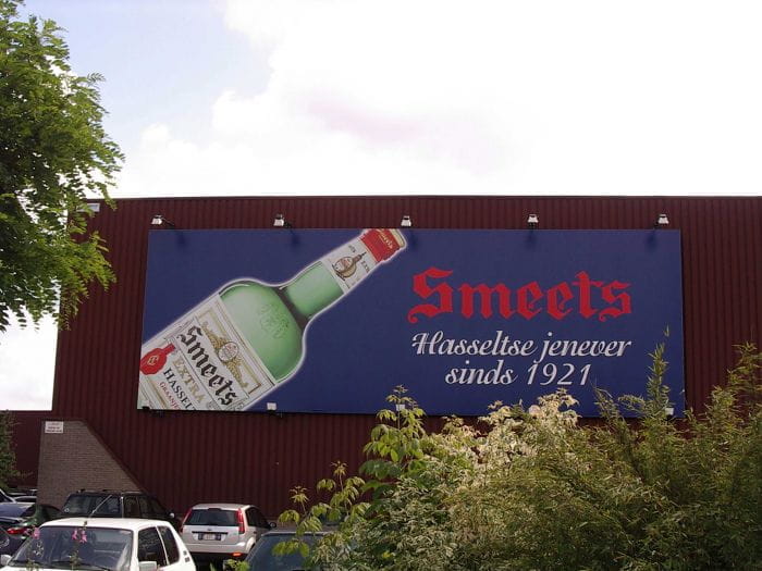 Banner Hauswand Banner mit der Aufschrift 'Smeets Hasseltse jenever seit 1921' und einer Abbildung einer Flasche.