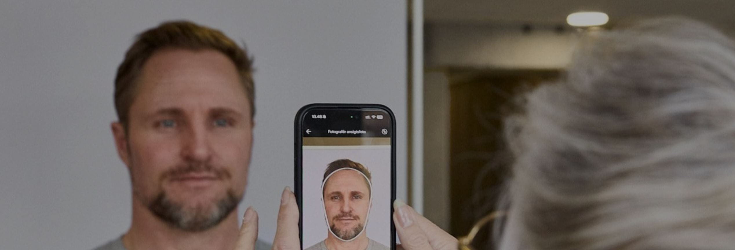 Ein Mann wird mit einem Smartphone fotografiert, das eine biometrische Gesichtserkennung zeigt.