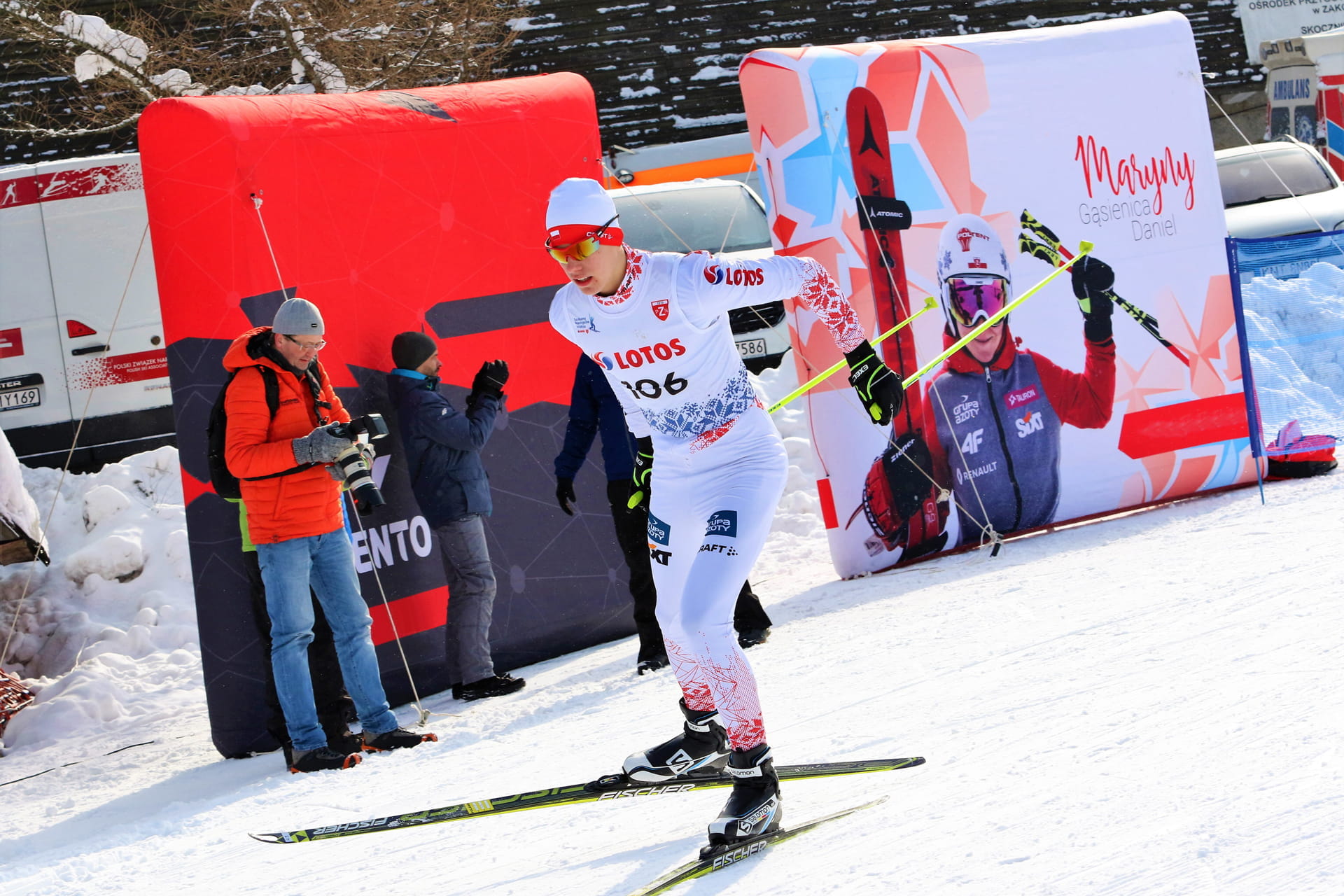 Vento Wand Wintersport Drei Sportler stehen auf dem Siegerpodest bei einem Wintersport-Event in Begpiastow, umgeben von Schnee und Bäumen.