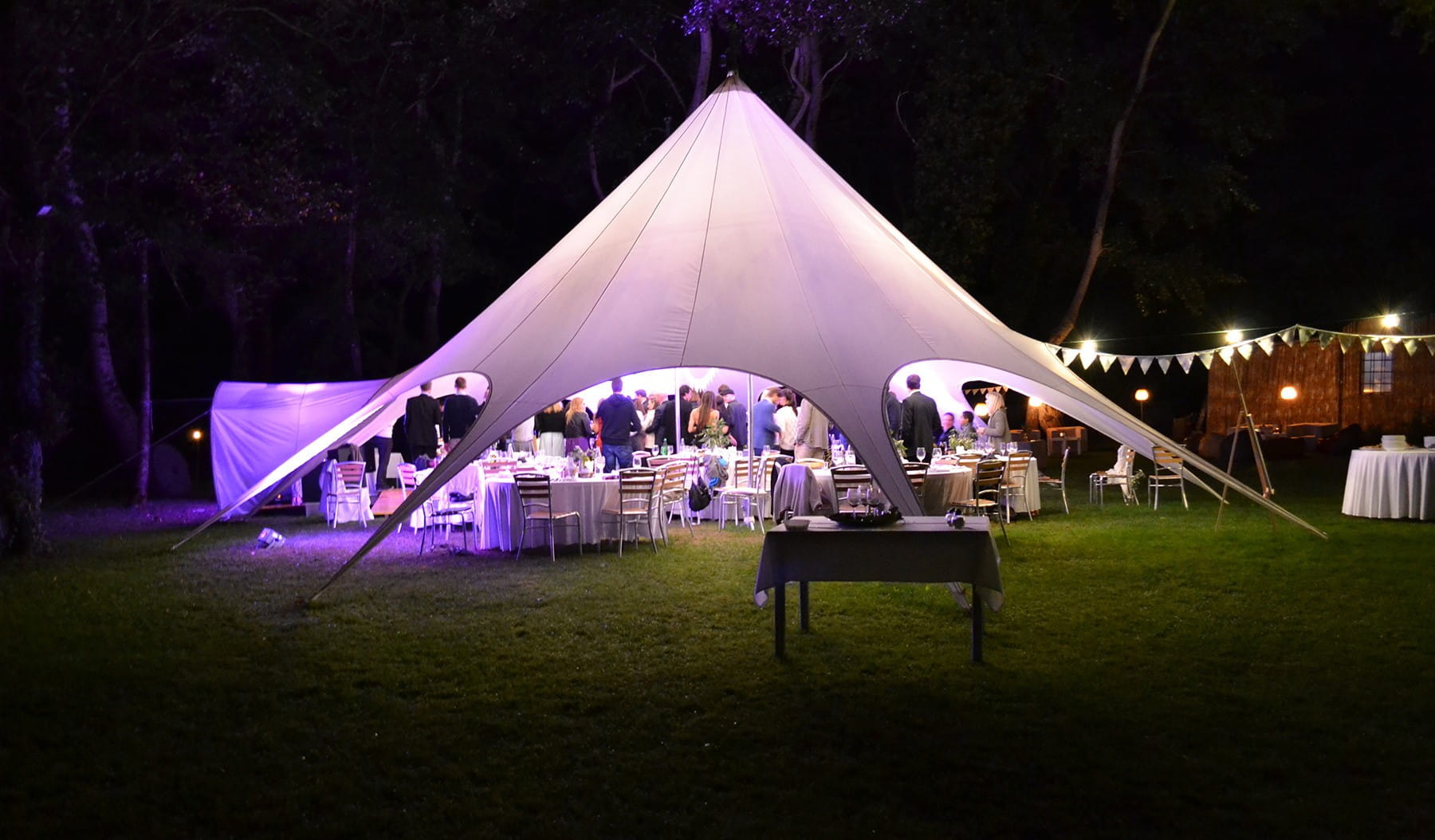 Sternzelt Jh Static Base Hochzeit Sternzelt Jh Static Base für Hochzeiten, auf einer Wiese mit festlich gedeckten Tischen und Beleuchtung.