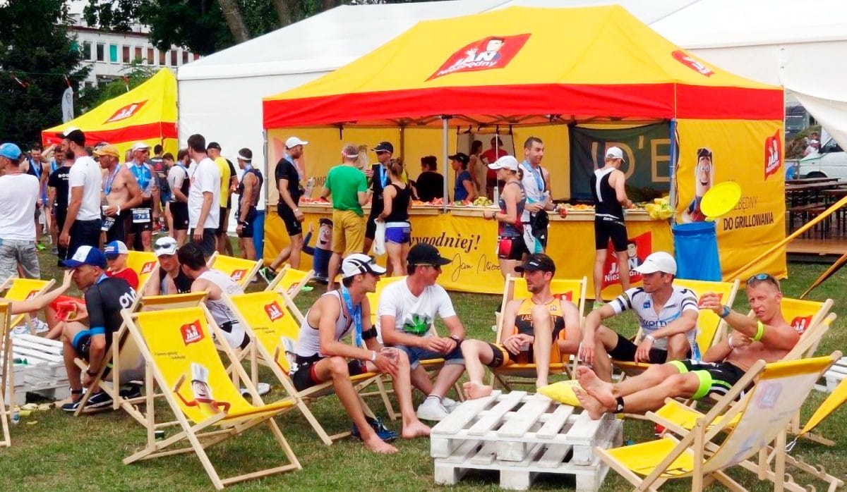 Faltzelt 3x6m Sommerfest Faltzelt 3x6m von ENTDECKER bei einem Sommerfest, mit Gästen in Sportkleidung und Liegestühlen.