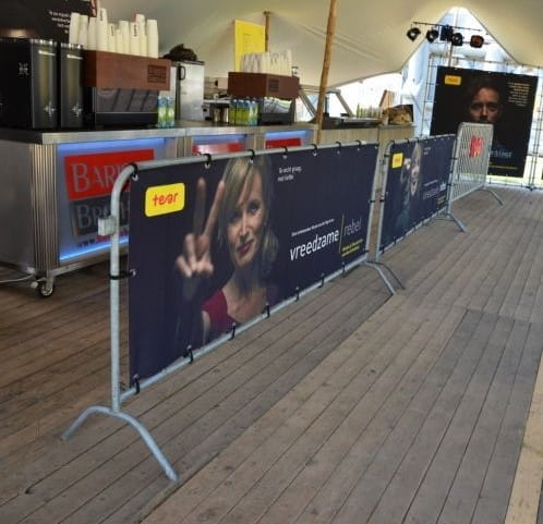 Absperrgitter Absperrgitter von ENTDECKER mit Werbebanner, auf einem Holzfußboden in einem Veranstaltungsbereich.