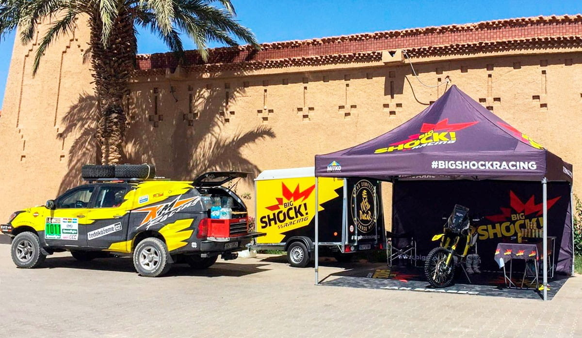 Faltzelt 3x3 bei Ralley Faltzelt 3x3 von ENTDECKER bei einer Ralley, mit einem gelben Fahrzeug und einem Anhänger im Hintergrund.