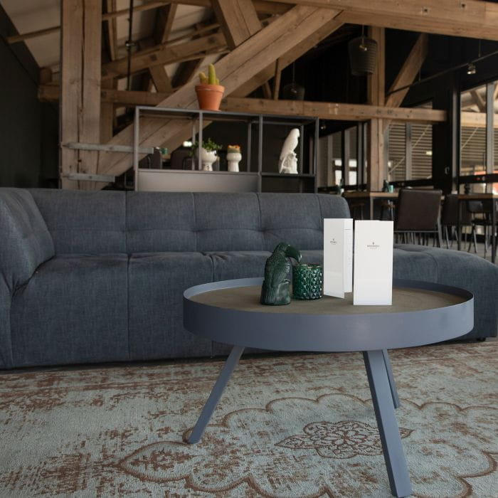 Sitzecke Gastronomie Sitzecke Gastronomie mit grauem Sofa und runder Tisch mit zwei weißen Karten auf einem Teppich.