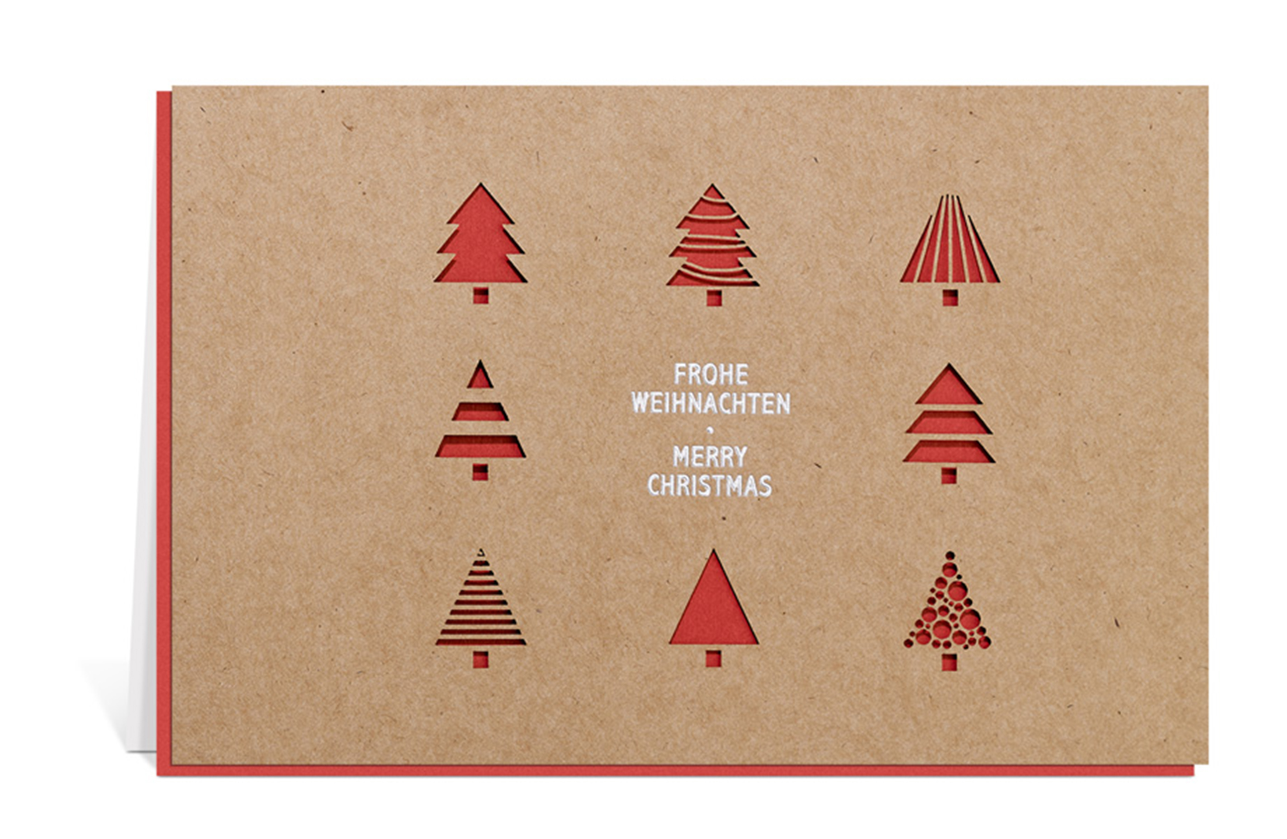 Weihnachtskarte aus Kraftpapier mit ausgestanzten Tannenbäumen und rotem Inlay, dazu der Text: Frohe Weihnachten - Merry Christmas