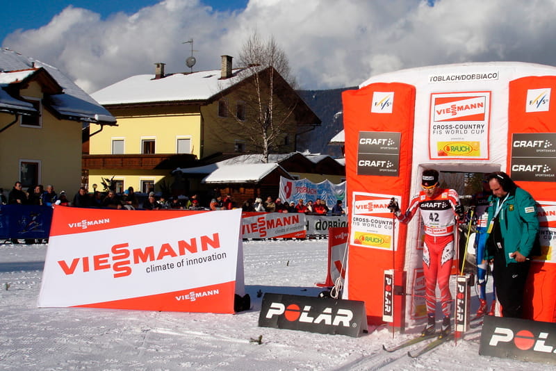 Werbebande Clickboard Winter bei Skirennen Werbebande für das Produkt 'Clickboard Winter' von ENTDECKER, präsentiert bei einem Skirennen mit Zuschauern im Hintergrund.