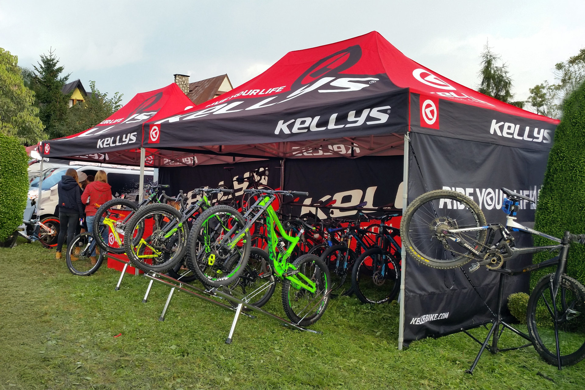 Bedrucktes Faltzelt mit Rennrädern auf einer Wiese mit Besuchern