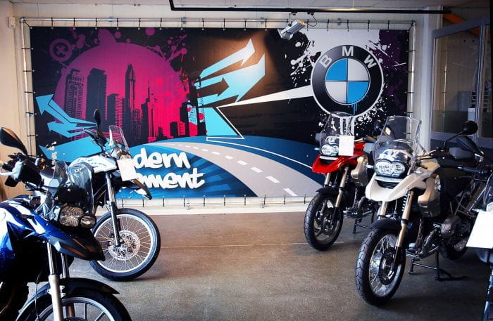 Banner Motorrad Banner mit BMW-Logo und urbanem Design, Motorräder im Vordergrund.