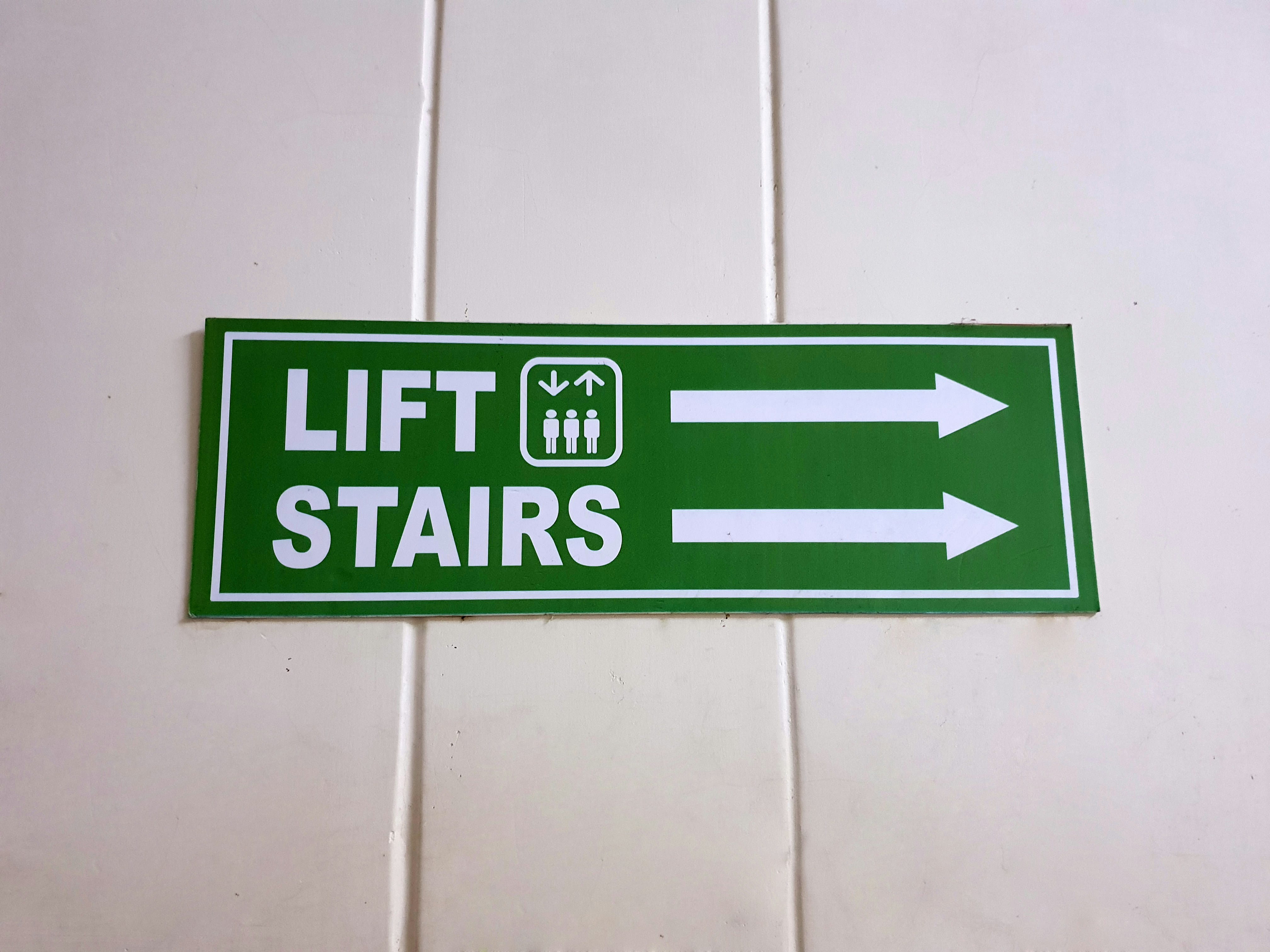 Werbeschild Treppen Grünes Werbeschild mit den Aufschriften 'LIFT' und 'STAIRS' sowie Pfeilen nach links und rechts.