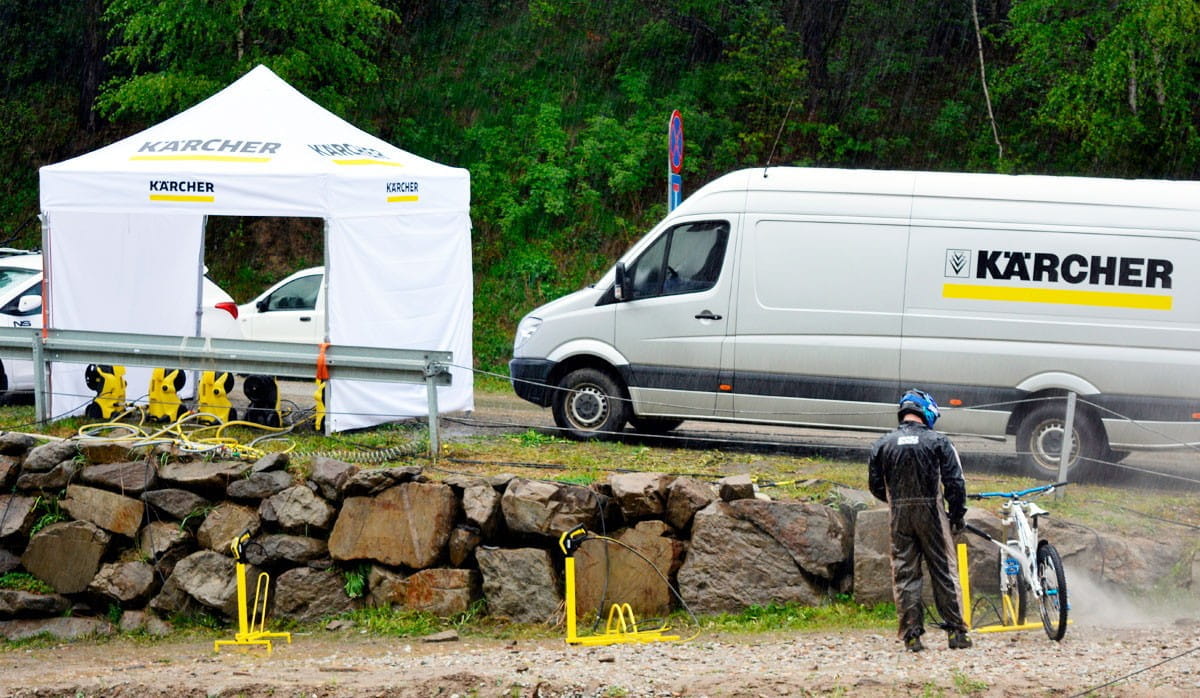Faltzelt Octa 3x3 Kärcher Faltzelt Octa 3x3 von Kärcher, aufgestellt neben einem Kärcher-Fahrzeug, mit einer Person, die ein Fahrrad reinigt.