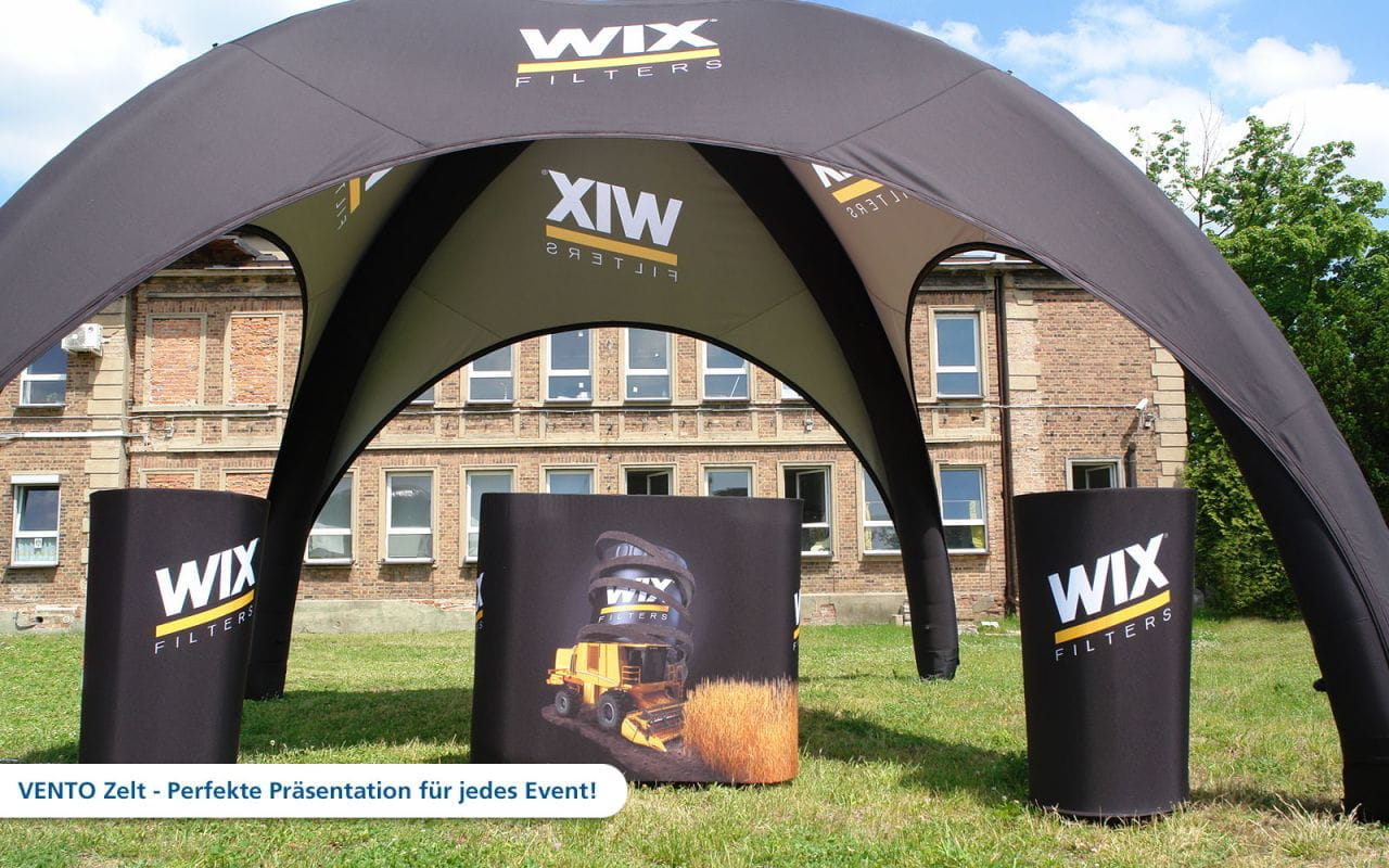 WIX Vento Aufblasbares Zelt Aufblasbares Zelt von WIX mit dem Produktnamen 'Vento' und Werbematerial für Filterprodukte, auf einer Wiese vor einem Gebäude.