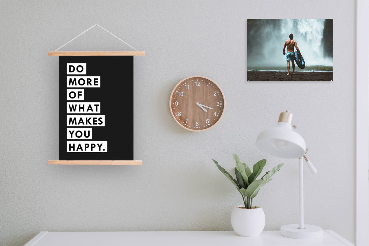 Poster und Wanddeko Wanddeko mit dem Text 'DO MORE OF WHAT MAKES YOU HAPPY', eine Uhr, eine Lampe und eine Pflanze auf einem Tisch.