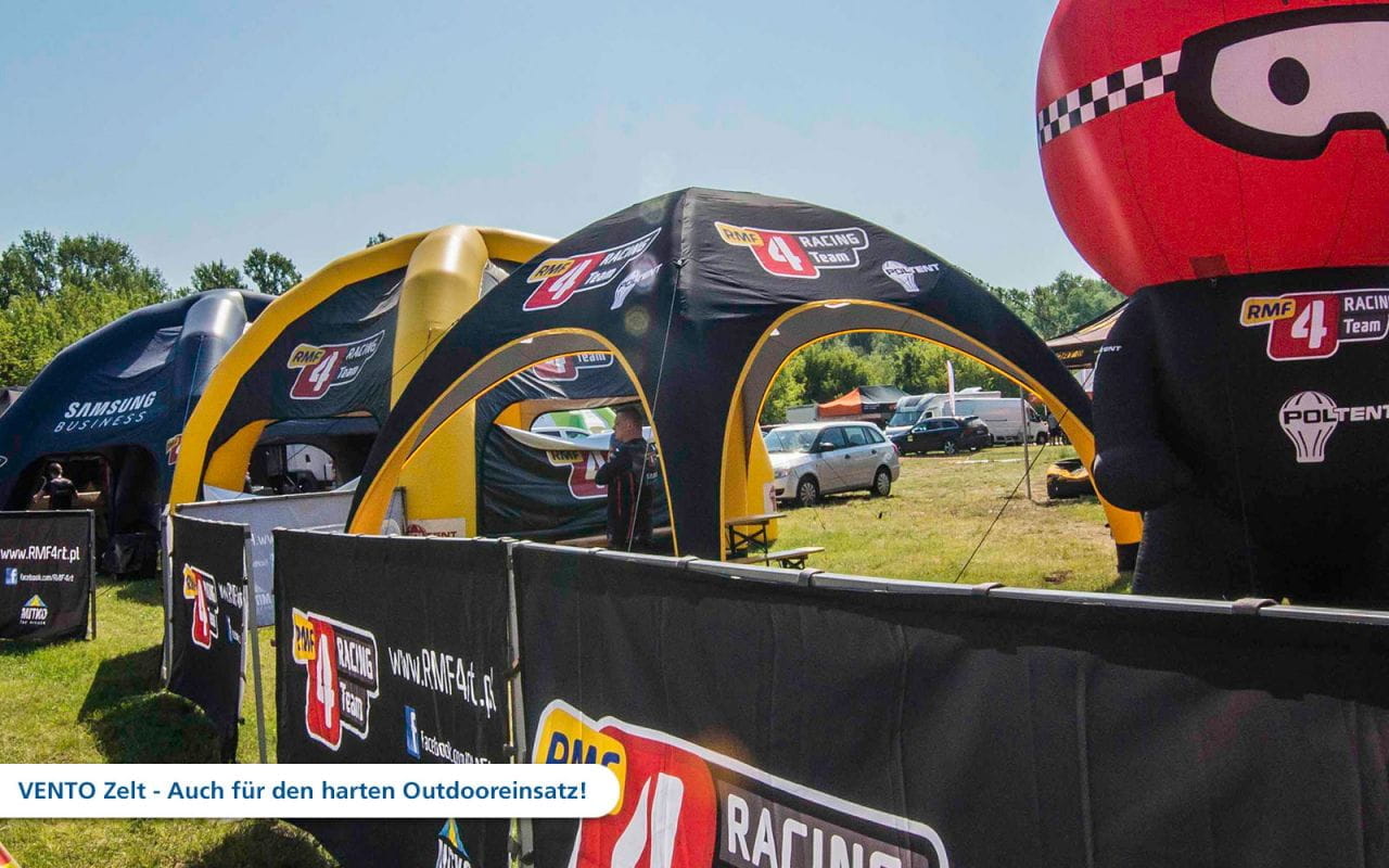 Vento Aufblasbares Zelt des RMF Racing Teams Aufblasbares Zelt von RMF Racing Team auf einem Outdoor-Event, mit verschiedenen Zelten und Fahrzeugen im Hintergrund.