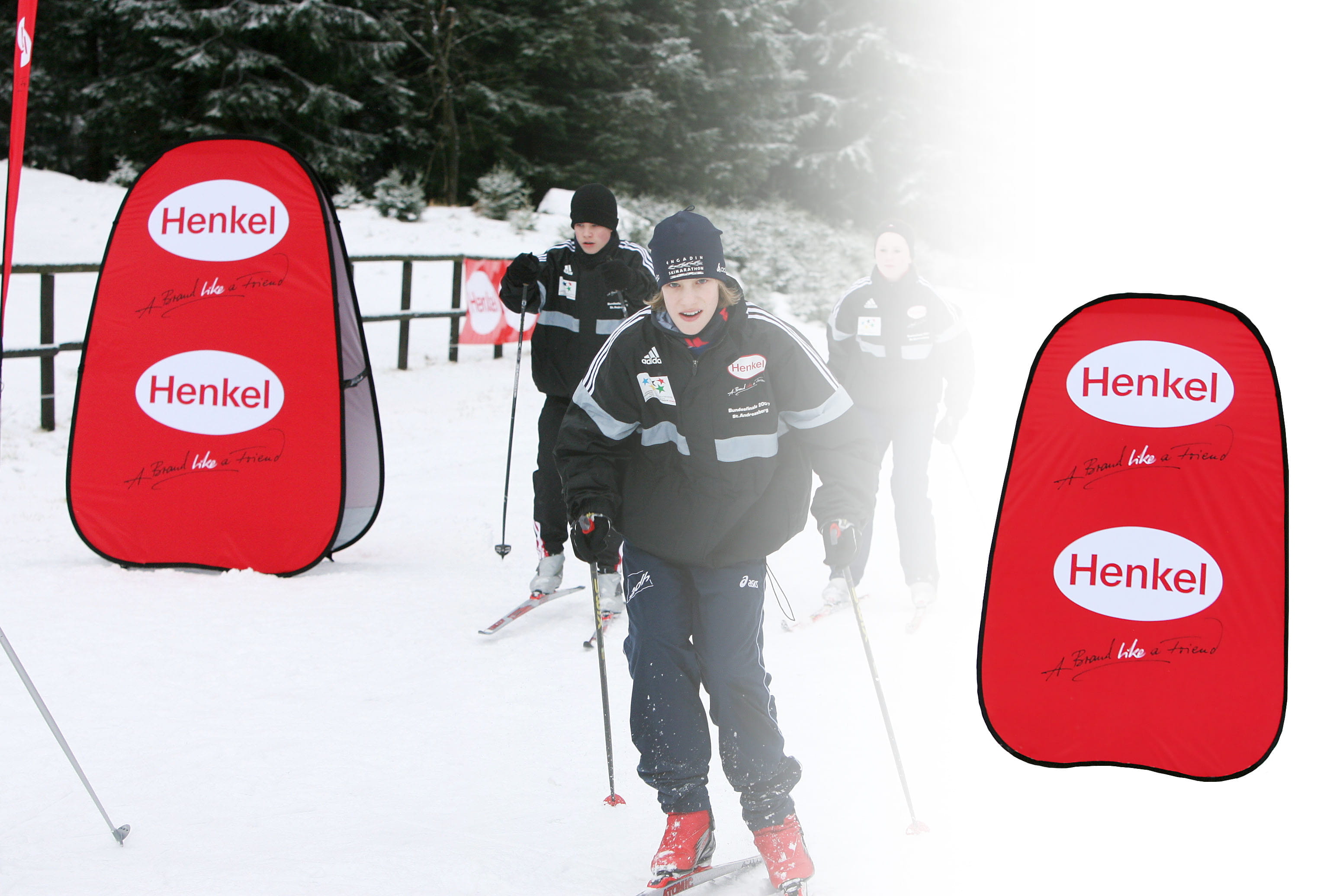 Werbebanden Quickboard Vertikal Henkel Werbebande Quickboard Vertikal von Henkel im Schnee mit Skifahrern im Hintergrund.