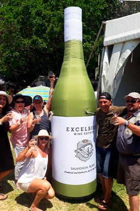 Gruppe mit übergroßer Flasche von Excelsior Wine Estate Gruppe von Menschen posiert mit einer übergroßen Flasche des Produkts 'Kleine Flasche' von Excelsior Wine Estate.