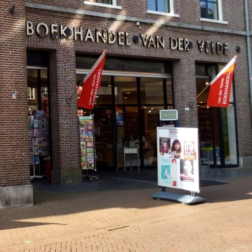 Kioskfahne Kioskfahne vor der Buchhandlung Van der Velde, mit roten Fahnen und Werbetafeln.