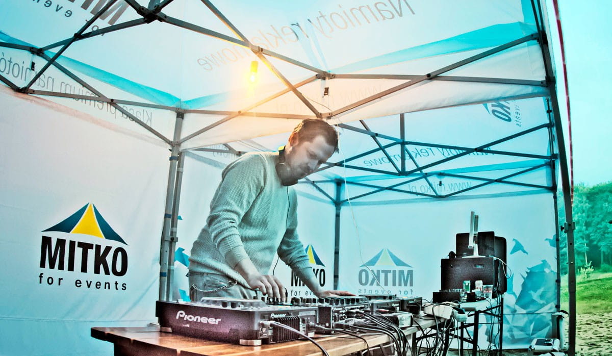 Faltzelt 3x6 bei Firmenfeier DJ steht an einem Mischpult unter einem Faltzelt mit dem Logo von MITKO bei einer Firmenfeier.
