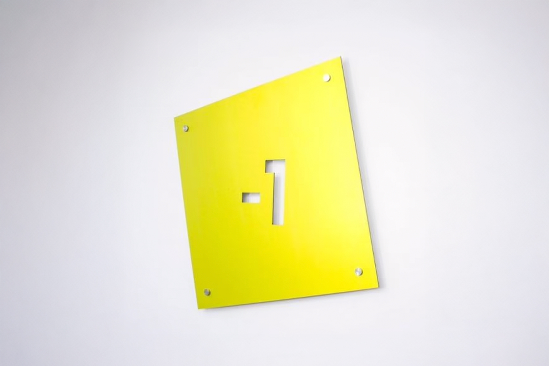 Gelbes Etagenschild mit einer ausgefrästen "-1" an der Wand
