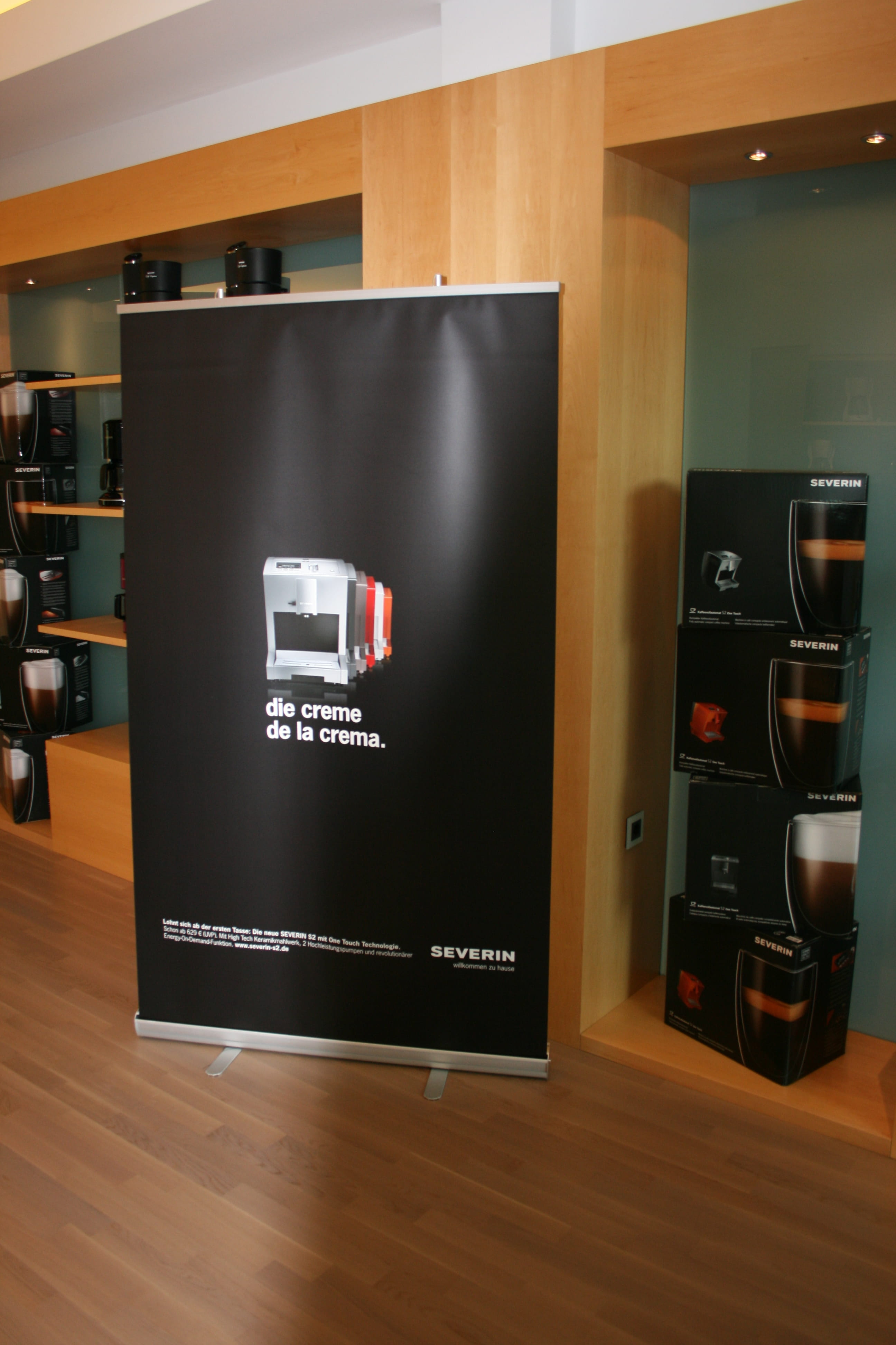 Roll-Up Banner mit dem Text 'die creme de la crema.' und einer Abbildung einer Kaffeemaschine von Severin.
