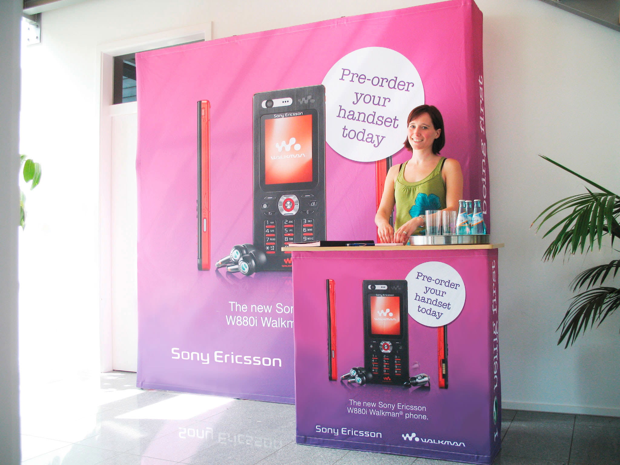 Messewand Quickup Stoffwand Medium Sony Messewand mit dem Produktnamen 'Quickup Stoffwand', zeigt eine Frau hinter einer Messetheke mit Werbung für ein Sony Ericsson Handy