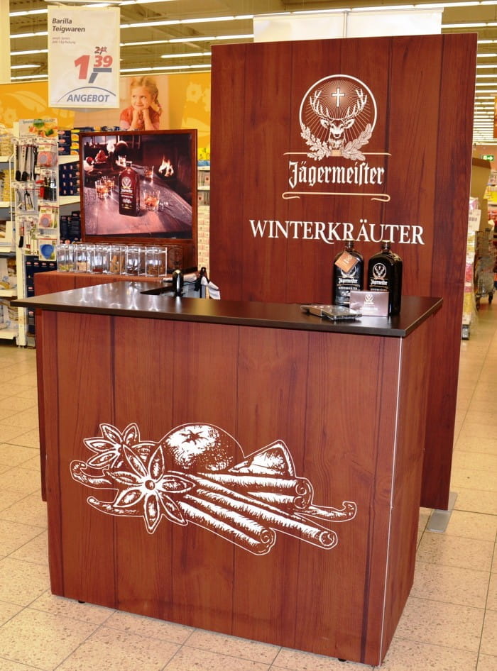 Jägermeister Messetheke Quickup Falttheke Pro Messetheke von Jägermeister mit dem Schriftzug 'WINTERKRÄUTER' und dekorativen Kräutermotiven, in einem Verkaufsraum.
