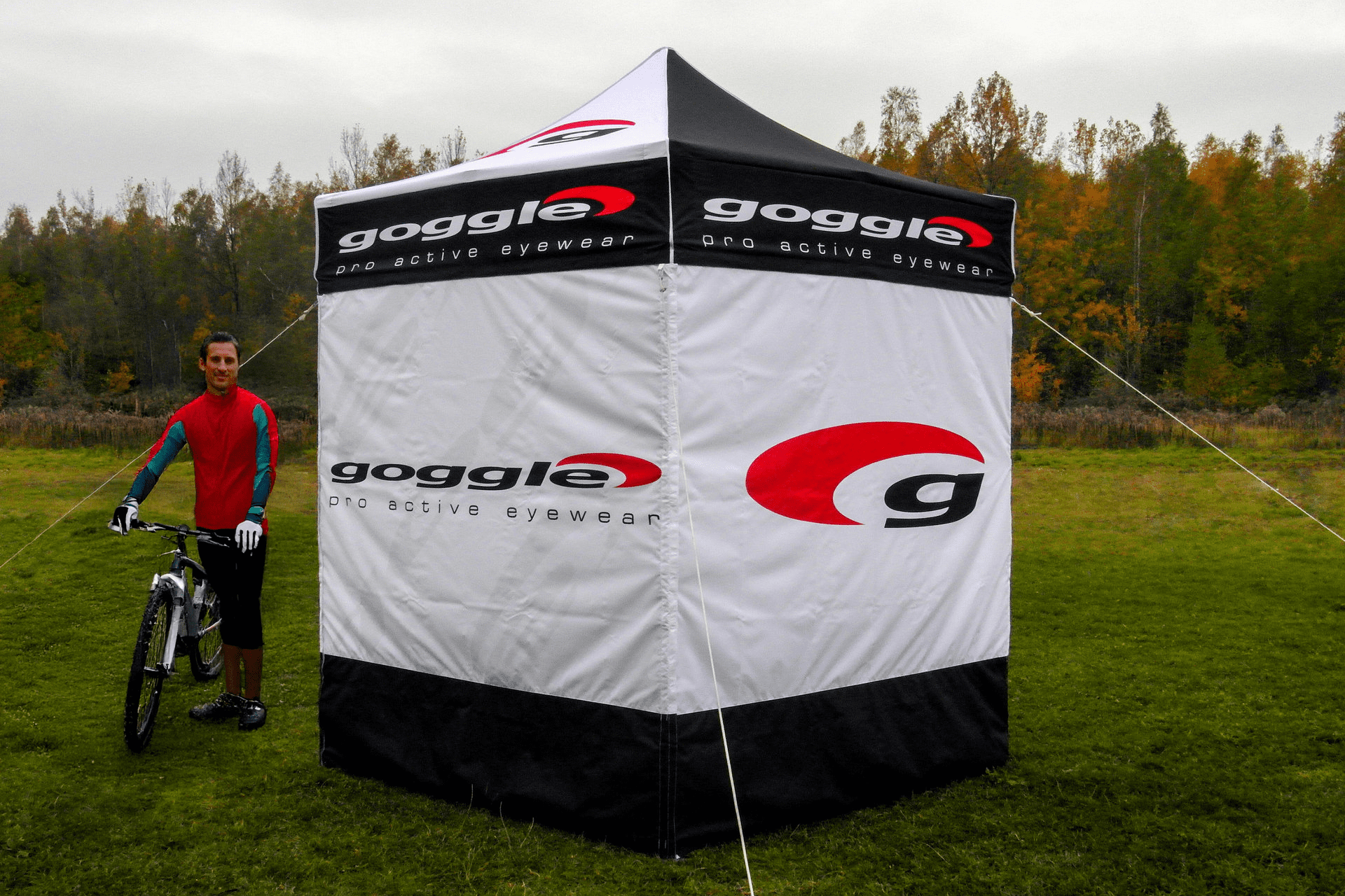 Falzzelt mit Logoaufdruck auf einer Wiese mit Rennradfahrer