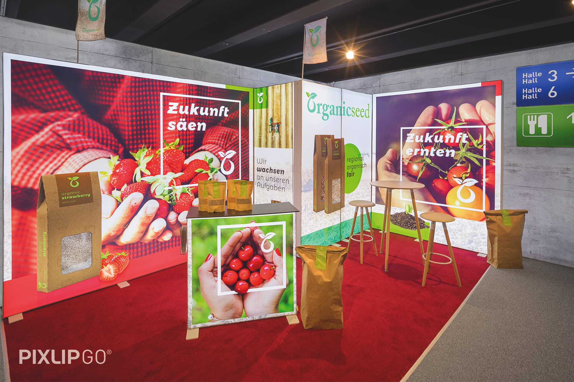 Ein Messestand aus Leuchtrahmen der Marke Pixlip mit Werbung für Beerensamen