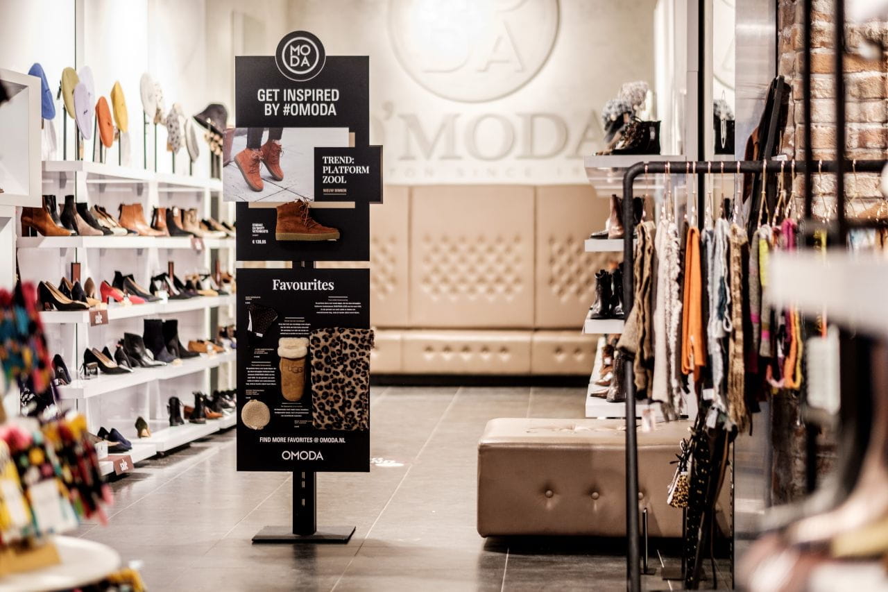 Inhaker POS Display in Modeboutique Inhaker POS Display in einer Modeboutique mit Schuhen und Kleidung im Hintergrund.