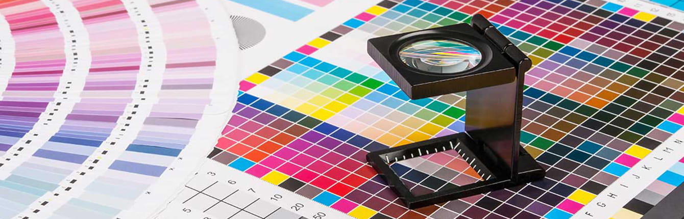 Druckdatenleitfaden & Tipps Ein Fadenzähler auf einem Farbmusterbogen mit verschiedenen Farbpaletten.